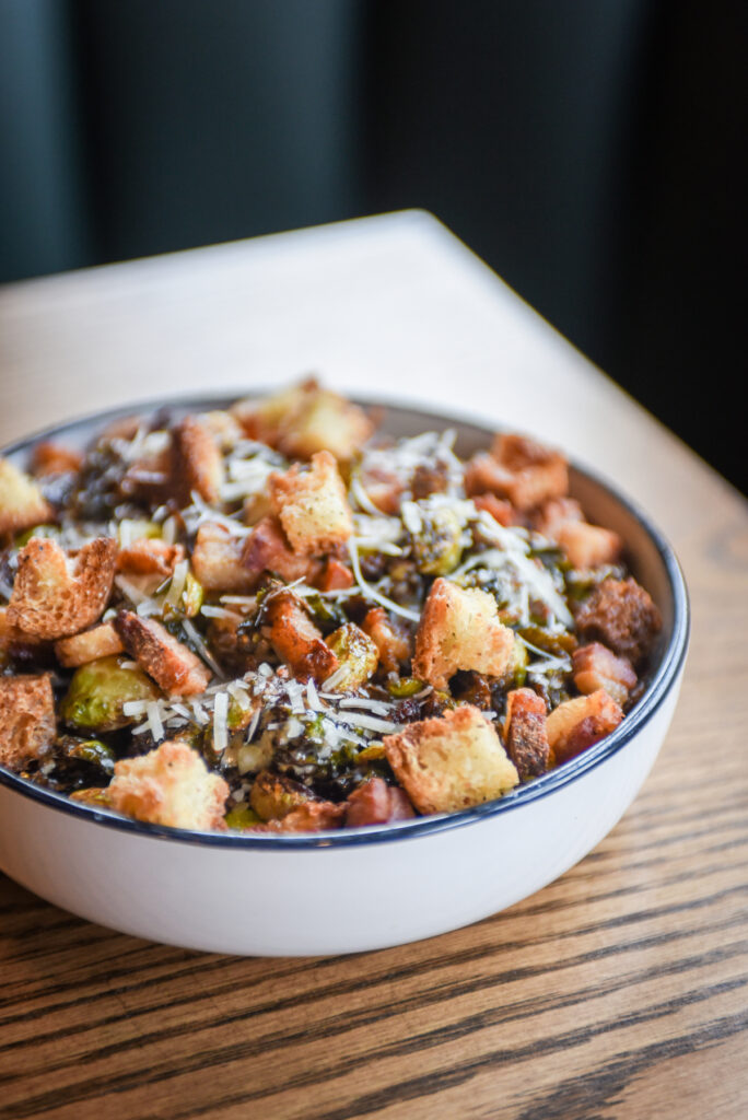 Crispy brussels sprout salad with bacon lardons, croutons, parmesan, and caesar dressing