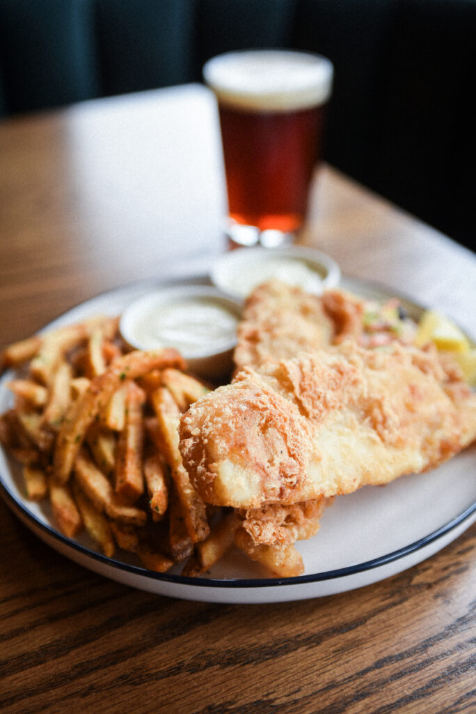 Two piece fish and chips served on a plate with window light