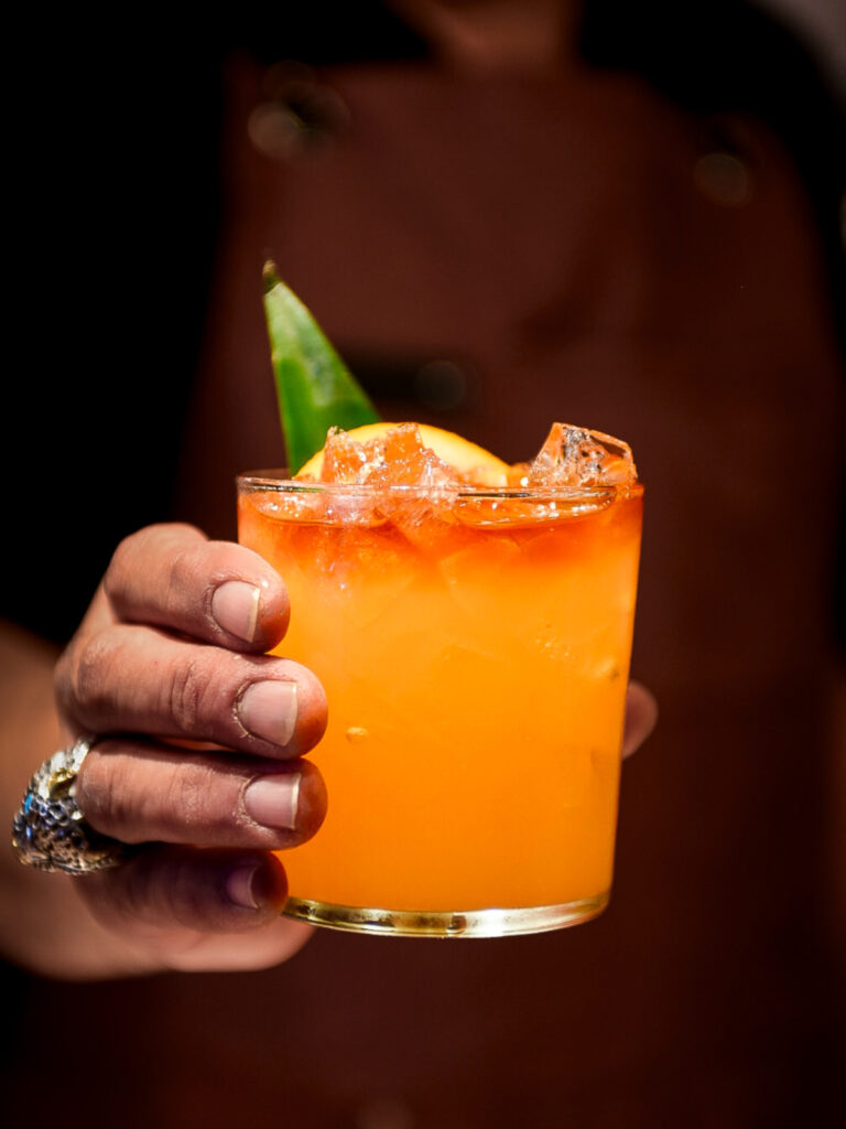 station taphouse bar manager holds a bright flavourful mai tai cocktail garnished with citrus and a pineapple frond