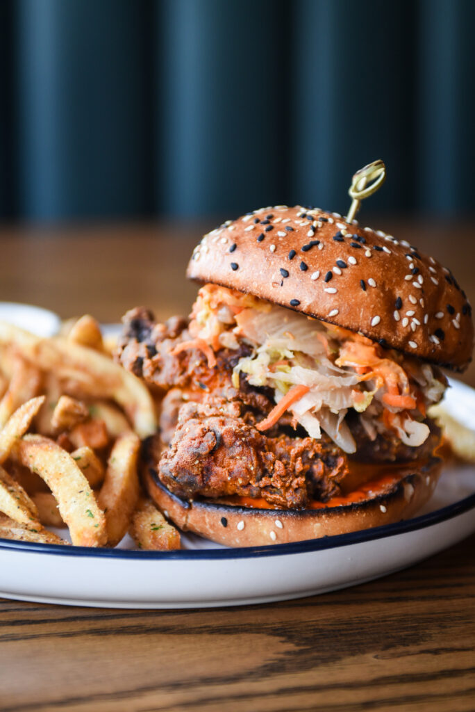 Korean fried chicken sandwich with fries on a plate in natural window light
